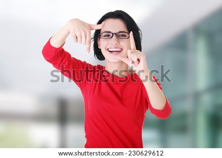 Smiling woman wearing red blouse is showing frame by hands
