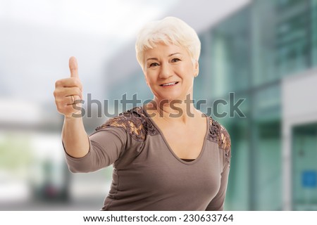 Old smiling woman showing OK