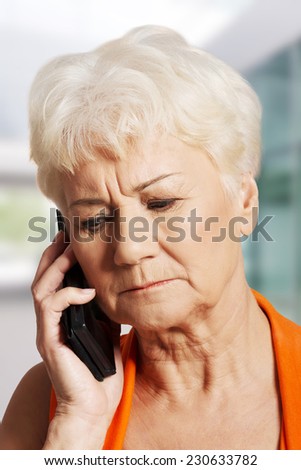 Old lady talking through phone, receiving bad news.