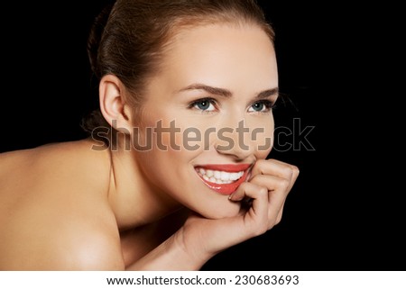 Portrait of smiling nude woman on dark background.