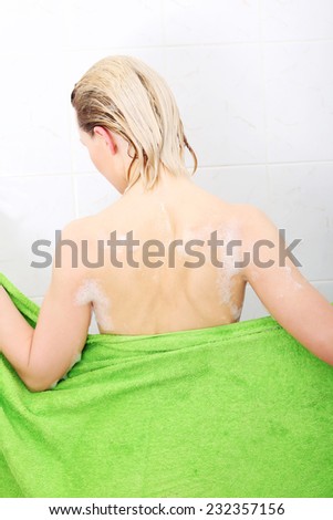 Back view woman wrapping in towel after bath.