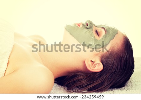 Beauty treatment in spa salon. Woman with facial clay mask. Isolated on white