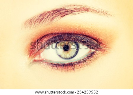 Female\'s open eye. Closeup. Skin coloured background.