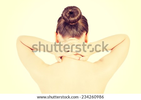 Naked beautiful woman holding her neck. Back view. Isolated on white.