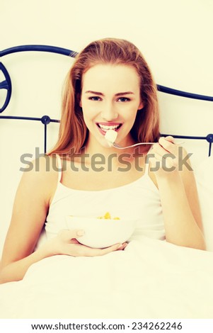 Beautiful caucasian woman eating fresh fruit for breakfast in bed.