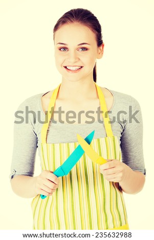 Attractive woman in kitchen apron with knives. Isolated on white.