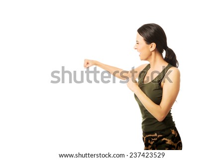 Woman hitting punching bag, shouting loud and wearing military clothes.