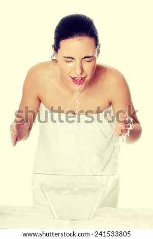 Young female washing her face with clear water.