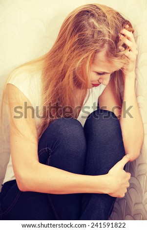 Scared abused woman sitting in the corner of the room.