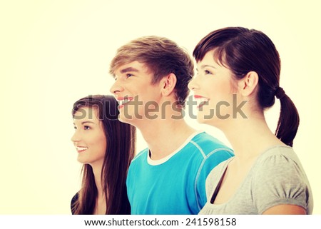 Three young happy friends. Two girls one boy smiling and looking left.