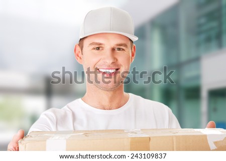 Young attractive courier guy delivering brown box