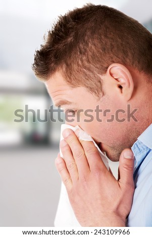 Sick young man blowing his nose