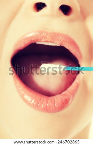 Young woman putting ear stick into mouth. Close up.