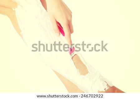 Slim woman is shaving her legs with foam and razor.