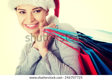 Beautiful young woman in santa hat with shopping bags.