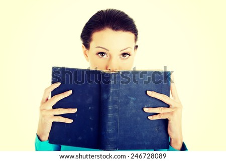 Beautiful young student woman holding a book on her face.