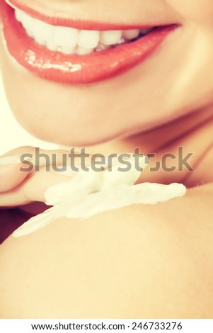 Beautiful woman applying body lotion on arm. Spa concept.