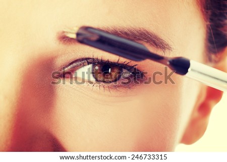 Beautiful woman brushing her eyebrow. Close up.