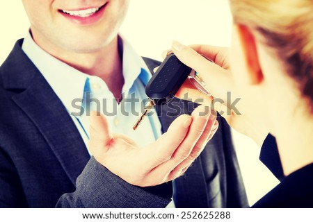 Car salesman handing over the keys for a new car to a young businessman