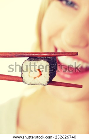 Happy woman eating tasty sushi