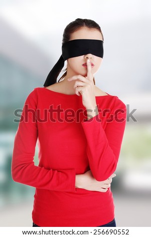 Blindfold woman with finger on lips
