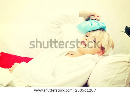 Woman in living room with ice bag having headache.