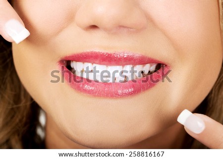 Young beautiful woman pointing on her perfect teeth.