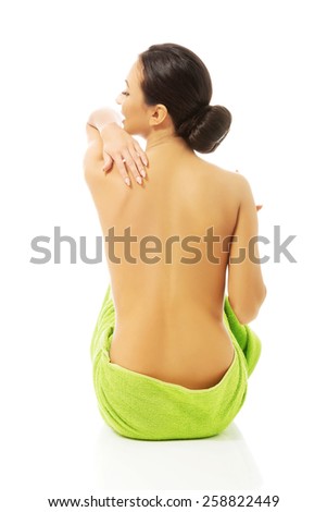 Back view woman sitting wrapped in towel.