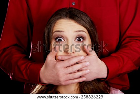 Scared woman has mouth covered by a man.