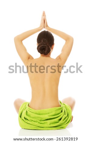 Back view of a woman practising yoga, wrapped in towel.