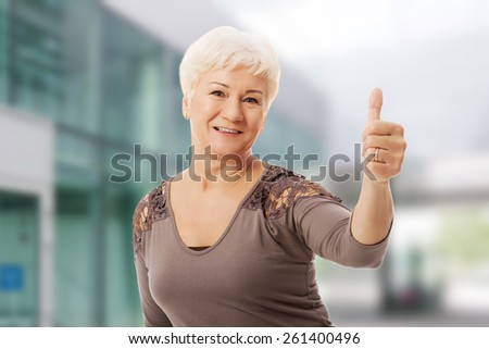 Old smiling woman showing OK