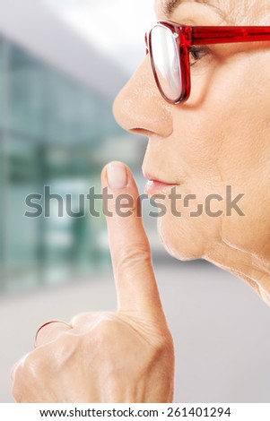 Elderly woman is having finger on her lips
