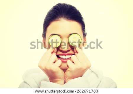 Beautiful young woman receiving facial mask of cucumber.