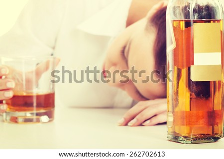 Alone young businesswoman in depression, drinking alcohol.