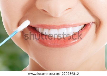 Young woman putting ear stick into mouth.