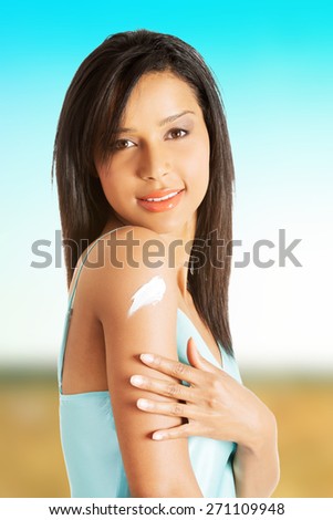Young woman applying cream on her shoulder.