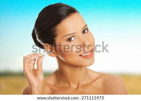 Woman cleaning ear using cotton stick.