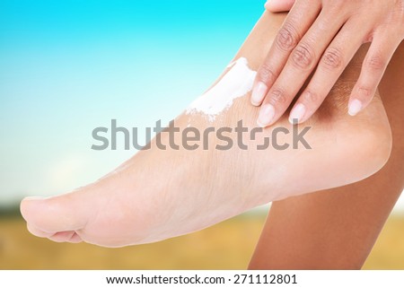 Young woman applying cream on her foot.