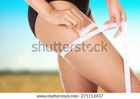 Slim woman measuring her thigh.