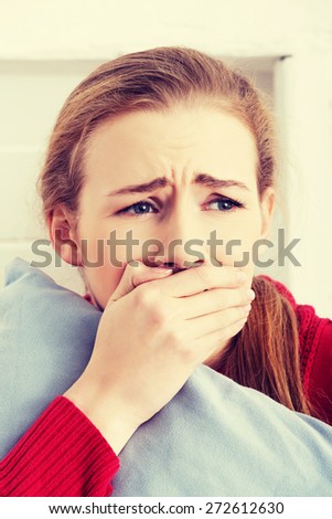 Beautiful caucasian scared woman holding a pillow