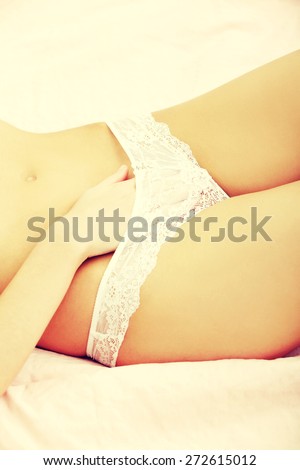 Slim young woman lying in bed wearing panties