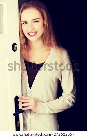 Young woman opening her house door