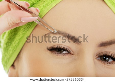 Beautiful caucasian woman plucking her eyebrow.