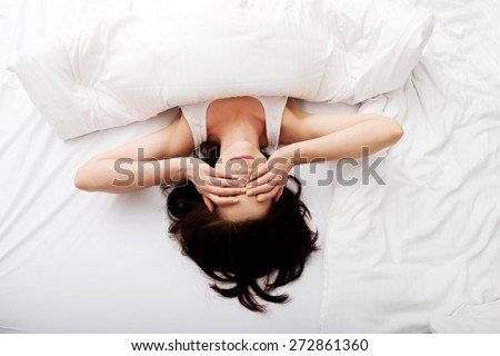 Sleepy brunette woman waking up and rubbing her eyes.