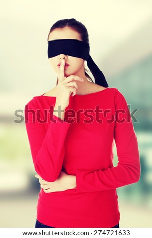 Blindfold woman with finger on lips