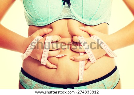 Overweight woman measuring her fat belly.