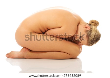 Nude woman curled up on the floor.