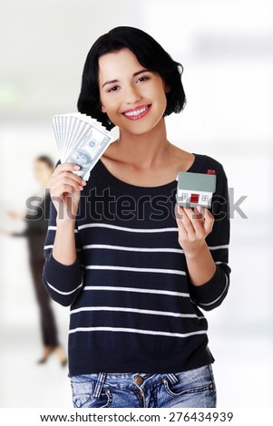 Happy woman holding dollar banknotes and house.