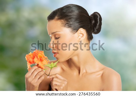 Beautiful exotic spa woman smelling orange flower.