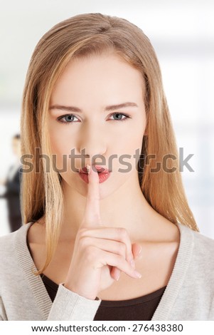 Woman gesturing to quiet with finger on lips.